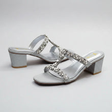 Load image into Gallery viewer, Silver glittery high-heeled sandals with rhinestone embellishments on a gray surface.
