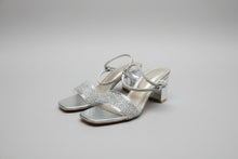 Load image into Gallery viewer, Pair of silver high-heeled sandals with glittery straps on a gray surface
