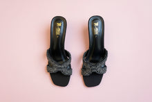 Load image into Gallery viewer, Black sandals with decorative straps on a concrete surface
