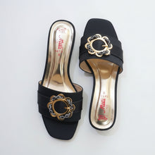Load image into Gallery viewer, Black high-heeled shoes with decorative gold buckle on a gray marble surface
